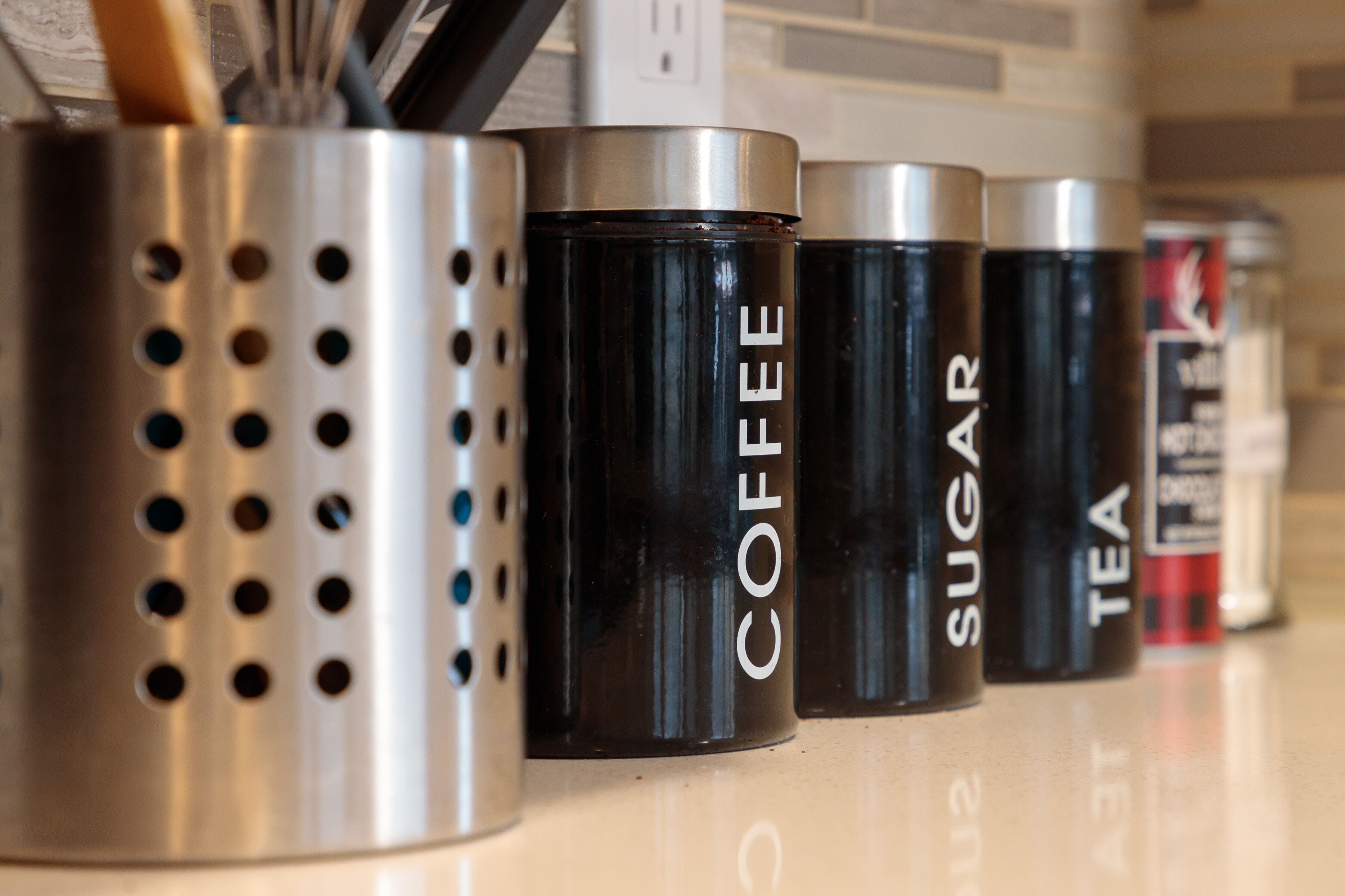 A row of stainless steel containers labeled with beverage types.
