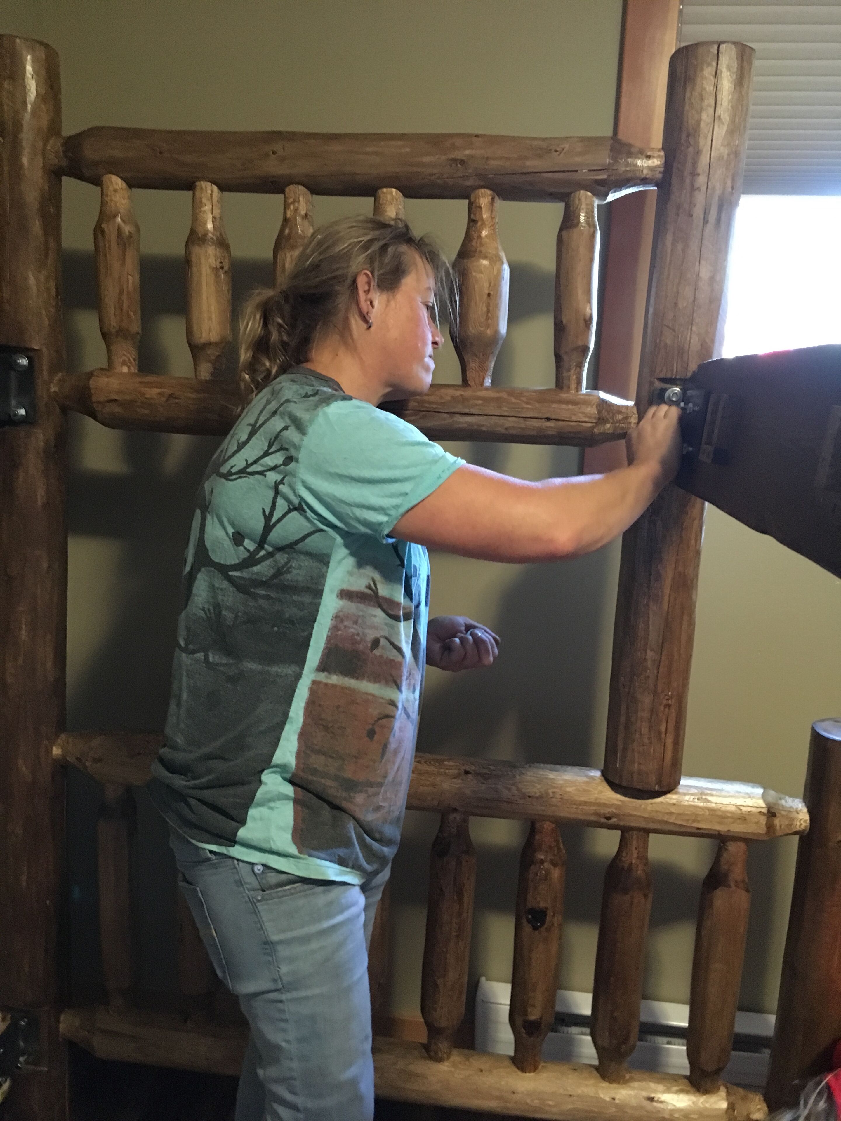 Une personne se tient devant une structure en bois composée de lattes verticales.