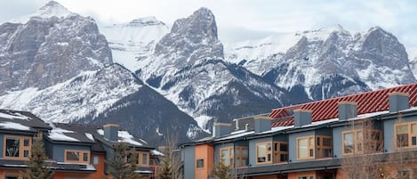 Un edificio de varios pisos con techo rojo, rodeado de montañas cubiertas de nieve.