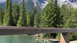 Eine Holzterrasse mit Blick auf einen klaren, türkisblauen See vor einer Bergkulisse.