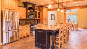 A spacious kitchen with wooden cabinets, stainless steel appliances, and a large island with bar stools. - SPACIOUS RETREAT NEAR YELLOWSTONE. FISHING, BOATING, HIKING, ATV & SNOWMOBILING (Island Park)