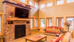 A cozy living room with a stone fireplace, a flat-screen TV, a sofa, and a coffee table. - SPACIOUS RETREAT NEAR YELLOWSTONE. FISHING, BOATING, HIKING, ATV & SNOWMOBILING (Island Park)