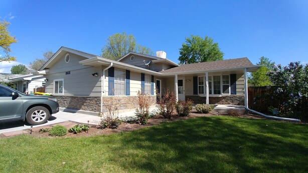 A two-story house with a stone facade, a covered porch, and a well-maintained lawn.