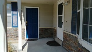 A front entrance with a blue door, a stone accent wall, and a small porch area.