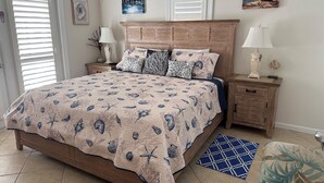 A bedroom with a bed, two nightstands, a dresser, and a window with blinds.