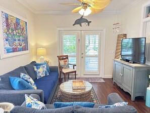Ein Wohnzimmer mit einer Couch, einem Fernseher, einem Deckenventilator und einem dekorativen Delphin, der von der Decke hängt.