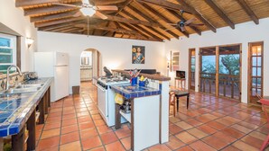 Una cocina amplia con una isla central, un comedor y vistas a través de grandes puertas correderas de vidrio.