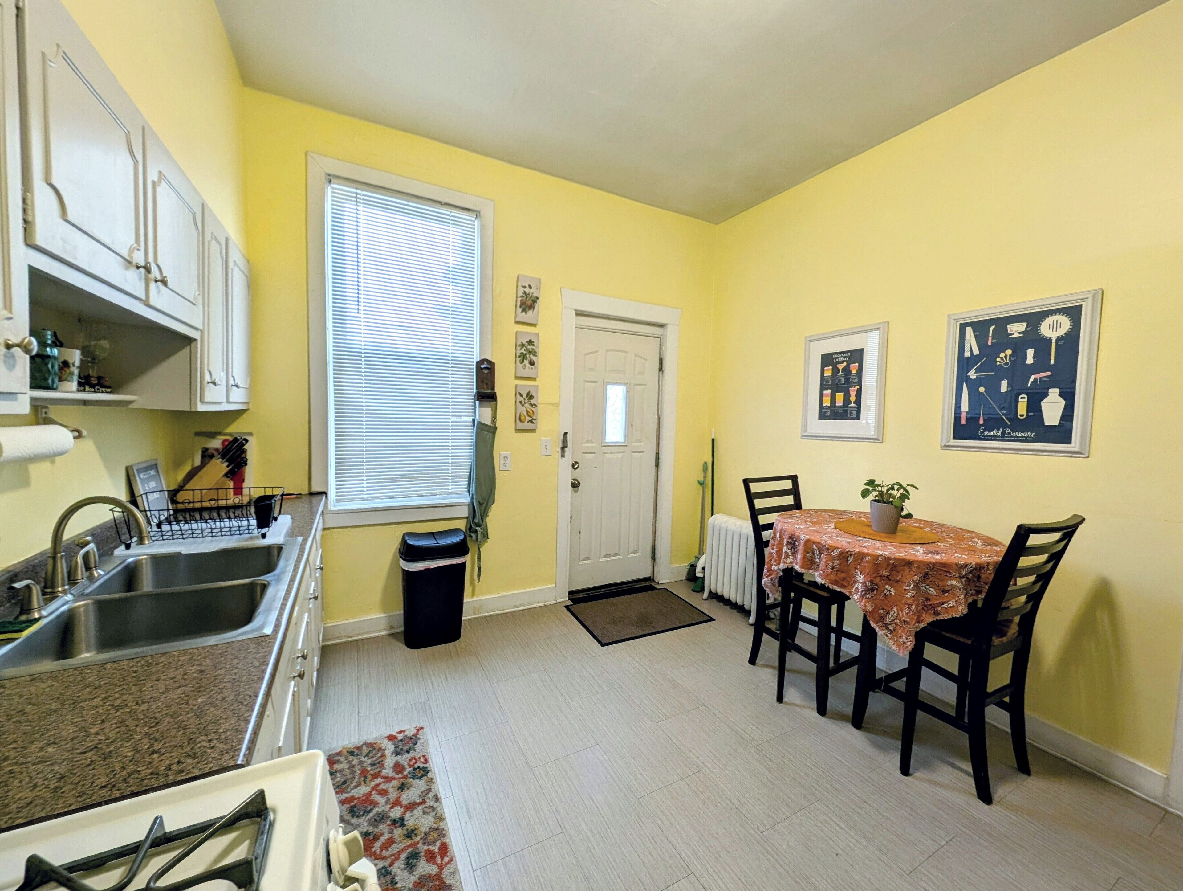 A compact kitchen with a sink, stove, and dining area with chairs and a table.
