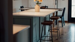 A modern kitchen with wooden beams, a central island with stools, pendant lighting, and a vase of flowers. - Gorgeous Mountain Views Retreat: Family & Nature (Hillsdale)