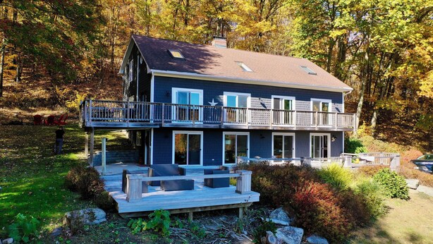 A two-story house with a balcony, a deck, and a view of the surrounding forest. - Gorgeous Mountain Views Retreat: Family & Nature (Hillsdale)