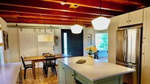 A kitchen with wooden floors, a central island, a stainless steel refrigerator, and pendant lighting. - Gorgeous Mountain Views Retreat: Family & Nature (Hillsdale)