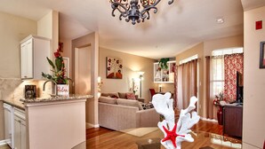 A modern kitchen with a built-in island, a dining area with a glass table, and a living room with a sofa and decorative items.