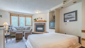 A bedroom with a bed, a sofa, a chair, a fireplace, and a TV. - Ski in / ski out family friendly condo w/access to pool, hot tub & game room (Winter Park)