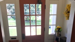 A hallway with a red door, a black doormat, and a radiator. - Day Street Suites. Historic Phelps Mansion.  Main Level Suite #2 (Decorah)