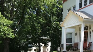 A well-maintained lawn, a porch with chairs, and a building with a number 408 sign. - Day Street Suites. Historic Phelps Mansion.  Main Level Suite #2 (Decorah)