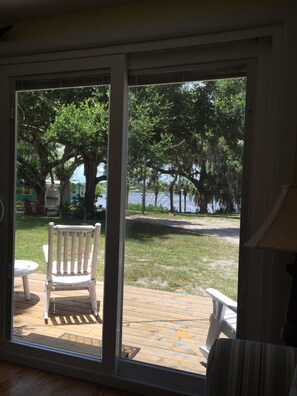 A room with a large sliding glass door leading to an outdoor deck with a wooden chair and a small table.