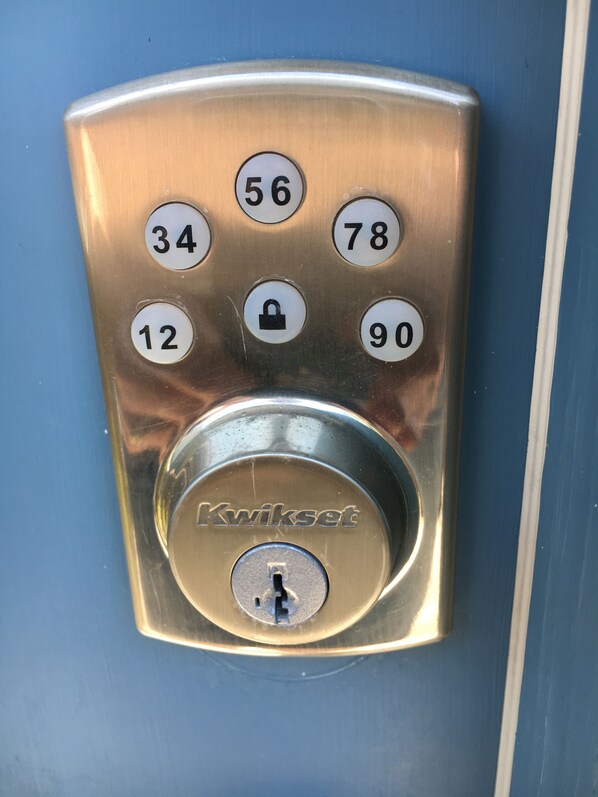 En Kwikset kombinationslås på en metaloverflade, hvor tallene 12, 34, 56, 78 og 90 er synlige.