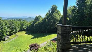 A stone pillar with a bench, overlooking a green field and distant mountains.