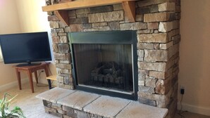 A stone fireplace with a television on a wooden stand to the left. - Beautiful Long Range Mountain Views, Minutes from Downtown Hendersonville, NC (Hendersonville)