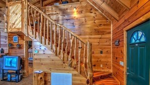 A wooden interior with a spiral staircase, a television, and a green door.