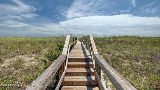 A wooden boardwalk leading to a beach with grassy dunes and a clear sky. - Right On the Beach - Spectacular Views! (Carolina Beach)