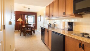 Una cocina con armarios de madera, microondas, cafetera y lavavajillas.