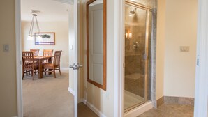 Un baño moderno con cabina de ducha de vidrio, un marco de puerta de madera y un comedor con candelabro.