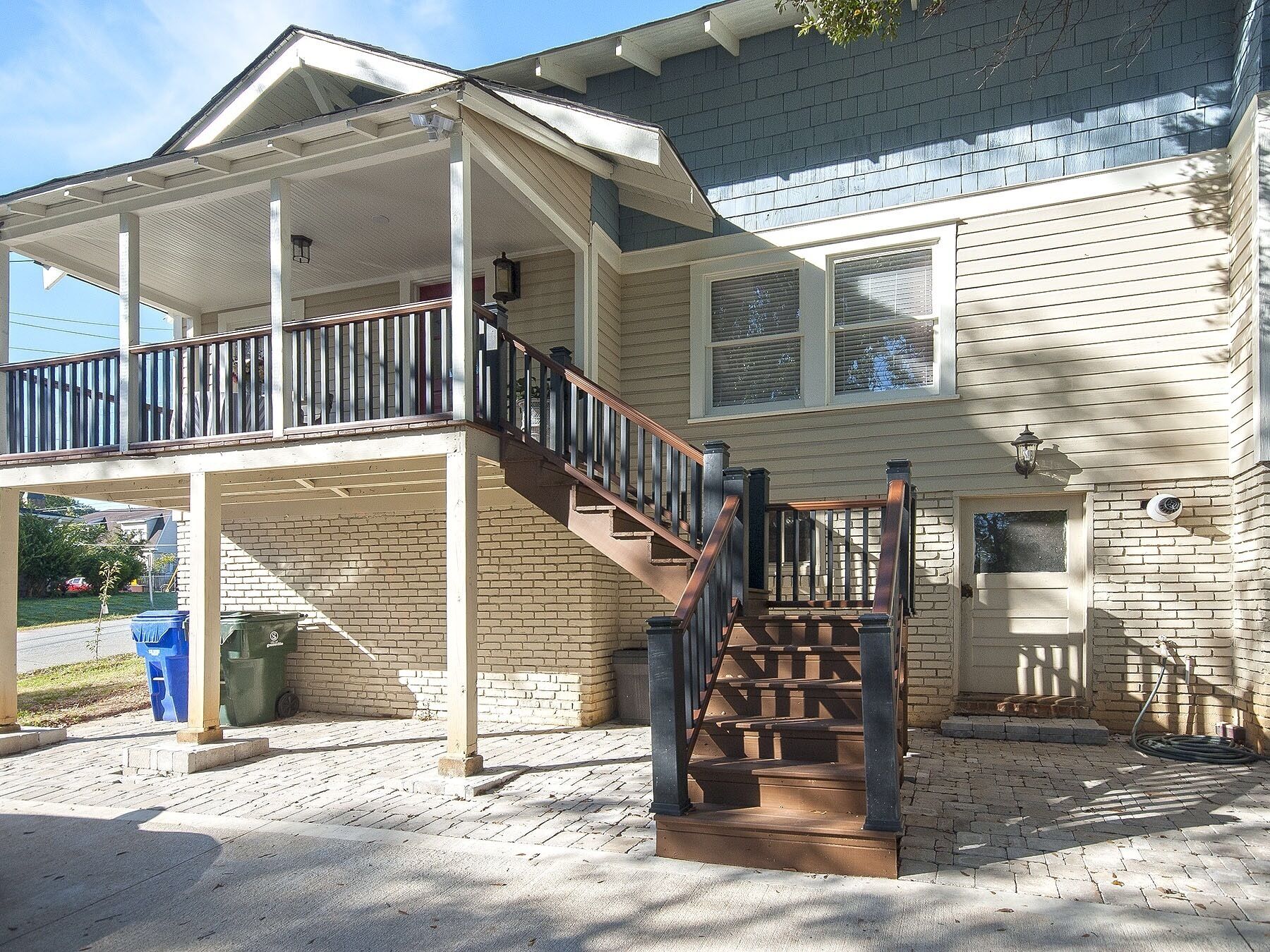 A two-story house with a covered porch and a wooden staircase.