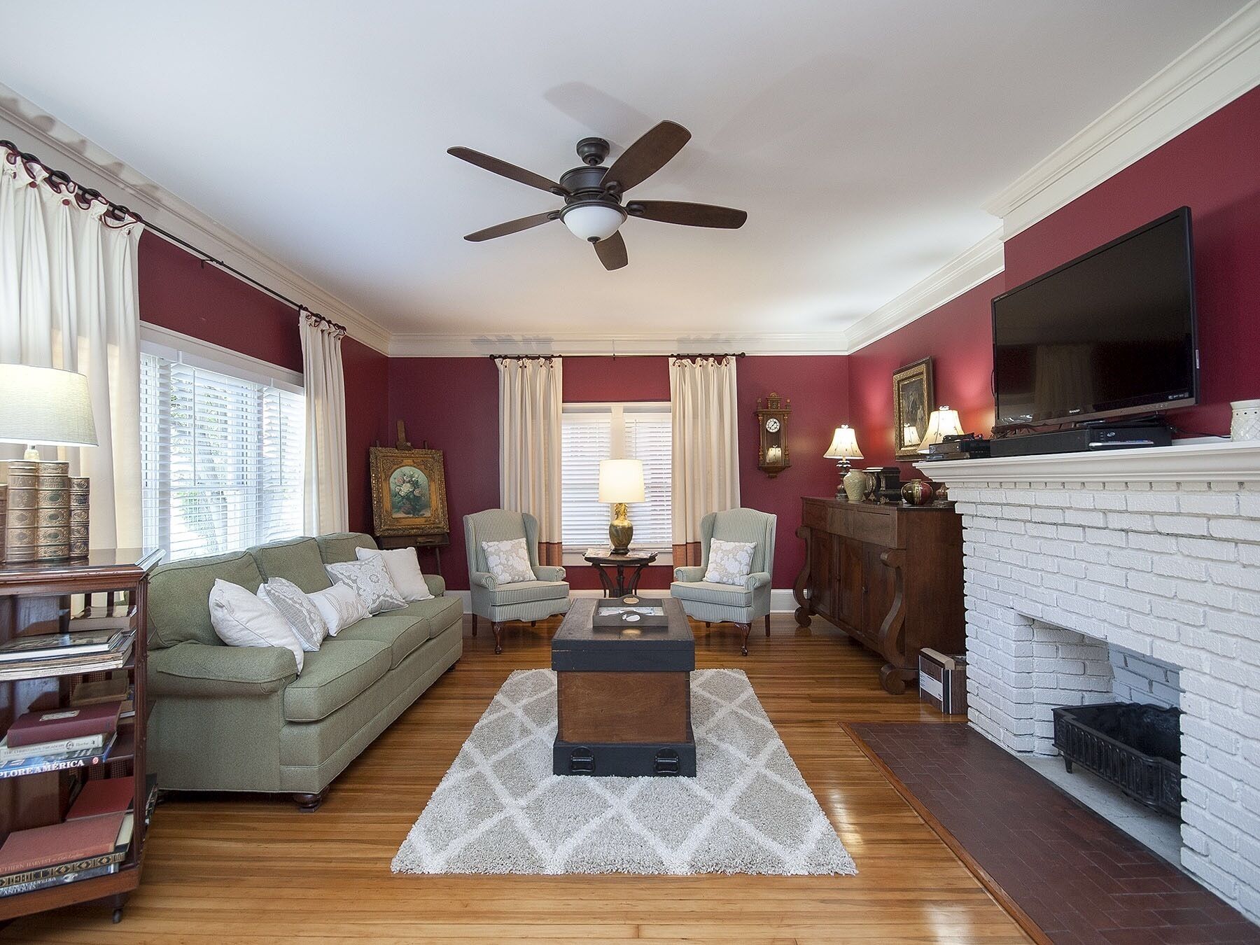 A living room with a green sofa, two armchairs, a coffee table, a fireplace, and a television.