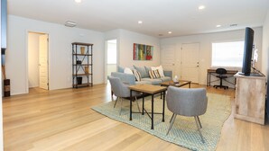 Un grand salon comprenant un canapé, des fauteuils, une table basse et un téléviseur posé sur un meuble.