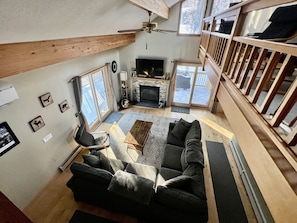 A spacious living room with a fireplace, large windows, and a high ceiling fan. - Mt. Snow Paradise - Indoor Jacuzzi & Sauna - Minutes to Mountain - Sleeps 10 (West Dover)
