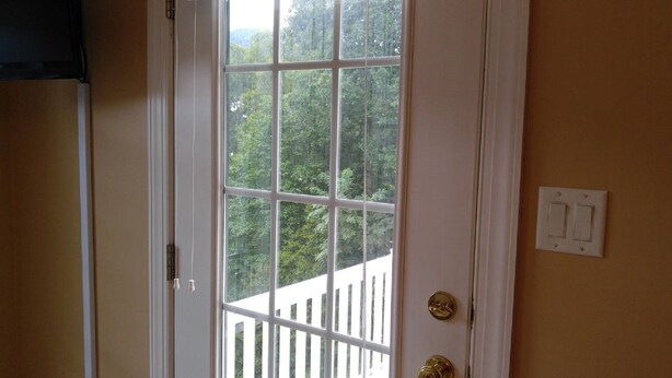 A white door with a view of a wooden deck and trees outside. - Beautiful Mountain views with private balcony close to Asheville, NC (Barnardsville)