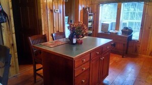 A wooden interior with a kitchen island, wooden chairs, and a dining table. - Secluded and Private Cabin with Amazing Views.  Hot tub and WiFi. (Lansing)