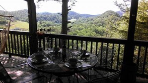 A dining table set for two with a scenic view of a forested landscape. - Secluded and Private Cabin with Amazing Views.  Hot tub and WiFi. (Lansing)