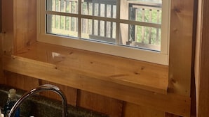A cabin with a wooden interior, a window with a view of a deck and trees, and the word "CABIN" above the window. - Secluded and Private Cabin with Amazing Views.  Hot tub and WiFi. (Lansing)