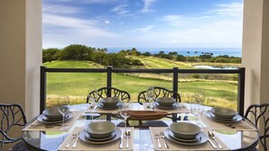 Taula de menjador preparada per a sis persones amb vista a un camp de golf i l'oceà.