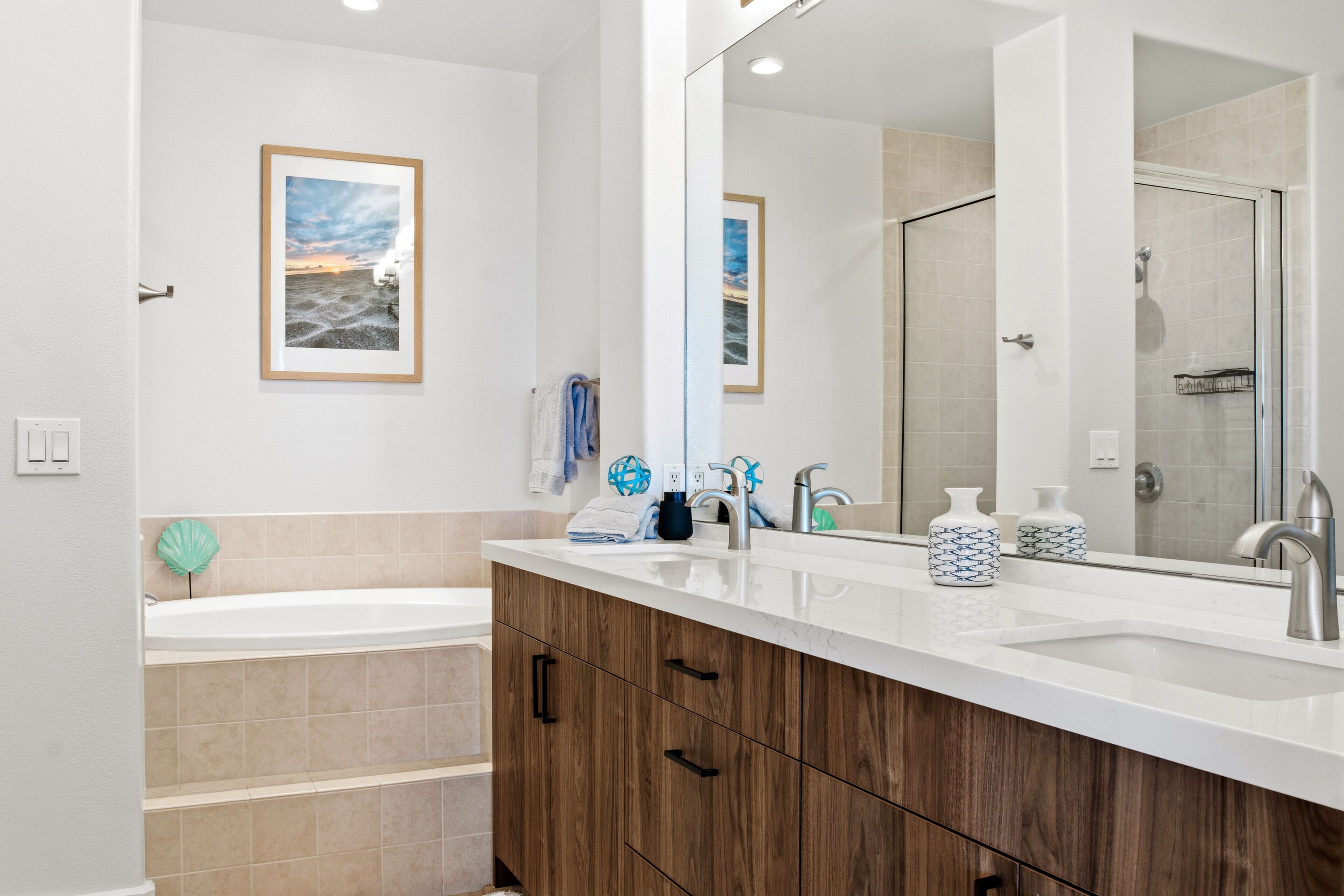 Une salle de bain moderne avec un grand miroir, des meubles en bois, une baignoire et un espace douche.