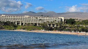 A beachfront hotel with multiple floors, a beach in the foreground, and mountains in the background. - NEWLY RENOVATED Popular Mauna Kea Condo - Spectacular Panoramic Ocean Views (Waimea)
