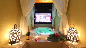 Une salle de bain avec une baignoire, une bouteille de champagne et deux lanternes décoratives.