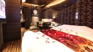 Une chambre d’hôtel avec un grand lit, une télévision, un jeu de fléchettes et un mur décoré de motifs.
