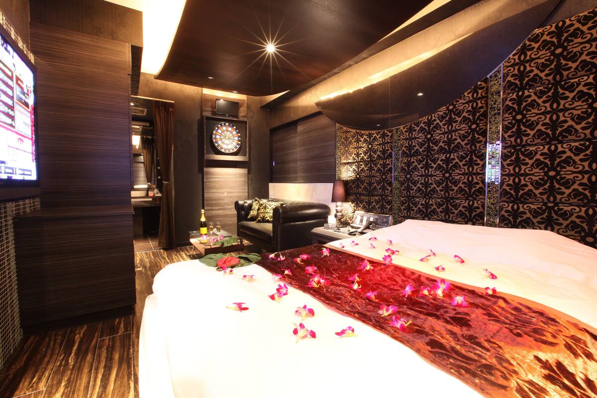 Une chambre d’hôtel avec un grand lit, une télévision, un jeu de fléchettes et un mur décoré de motifs.
