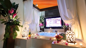 Une salle de bain aménagée comme un spa, avec une baignoire, deux vasques, une grande plante en pot et un éclairage décoratif.