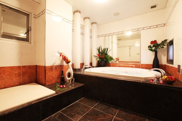 Un baño moderno con una bañera grande, lavamanos separado y tocador.