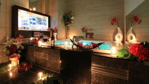 A hotel reception area with a digital display, a reception desk, a hot tub, and decorative flowers. - HOTEL GRASSINO URBAN RESORT URAWA - Adult Only (Saitama)