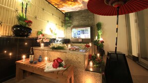 A reception area with a wooden bench, a red umbrella, and a wall with a digital menu board. - HOTEL GRASSINO URBAN RESORT URAWA - Adult Only (Saitama)