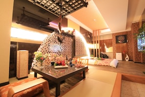 A traditional Japanese-style room with tatami flooring, a low table with a vase of flowers, a futon bed, and a dartboard on the wall. - HOTEL GRASSINO URBAN RESORT URAWA - Adult Only (Saitama)