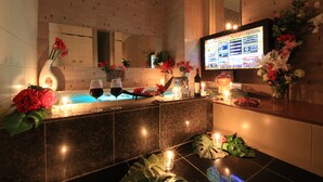 A modern bathroom with a marble countertop, a large mirror, and a television displaying a menu. - HOTEL GRASSINO URBAN RESORT URAWA - Adult Only (Saitama)