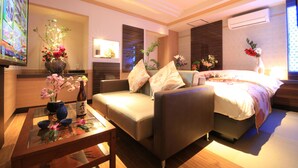 A modern hotel room with a sofa, a bed, a TV, and a vase with flowers. - HOTEL RIRAKU - Adult Only (Tokorozawa)