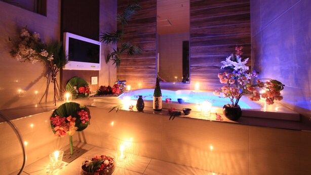 A modern spa area with a hot tub, candles, and floral arrangements. - HOTEL RIRAKU - Adult Only (Tokorozawa)