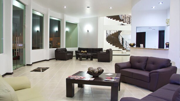 A spacious living area with a modern design, featuring a large sofa, a coffee table, and a staircase in the background. - Hotel Osalle Inn (Chignahuapan)